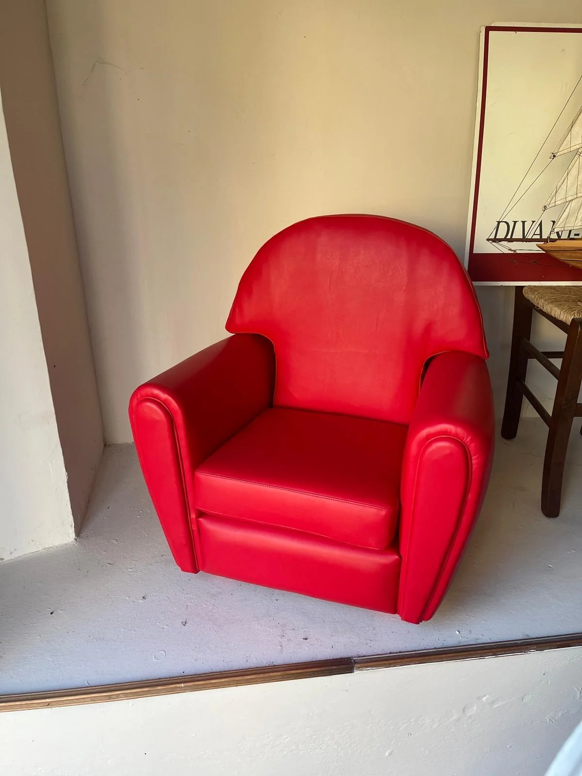 Poltrona con rivestimento rosso e schienale curvo nell’esposizione Costella